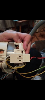 Zdjęcie silnika z przewodami i złączem elektrycznym, trzymanego w dłoni.