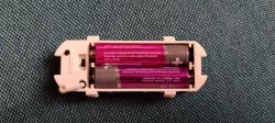 Close-up of an open battery holder with two AA batteries inside.