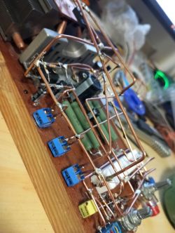 Samodzielnie zbudowany wzmacniacz z elementami elektronicznymi na drewnianej podstawie.
