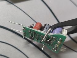 Close-up of PCB with electronic components held by metal tweezers