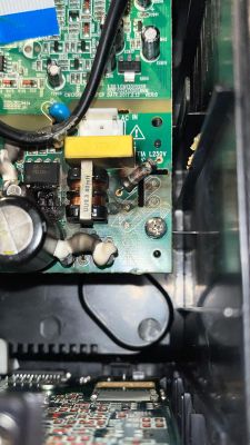 Foto eines verbrannten Bereichs einer Leiterplatte mit elektronischen Bauteilen, darunter eine „UU9.8 40mH“-Drossel, eine Sicherung und Kondensatoren.
