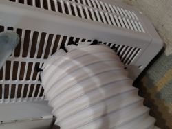 White flexible duct hose fastened with zip ties to a device ventilation grille