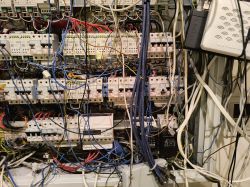 Skomplikowana instalacja elektryczna z licznymi przewodami i urządzeniami.