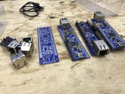 Kilka niebieskich płytek PCB oraz złącza Ethernet typu RJ45 leżące na drewnianym stole.