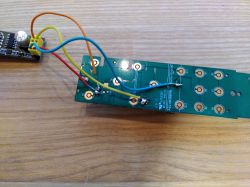 Circuit board with soldered wires placed on a wooden surface.