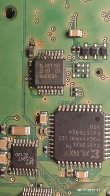 Zbliżenie na fragment płytki PCB wzmacniacza BMW z widocznymi układami scalonymi NXP HCT193, Xilinx i pustym polem po usuniętym elemencie SMD 0603.