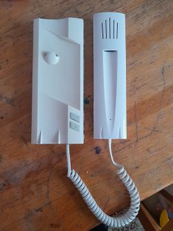 Intercom Handsets on Surface Image of two white intercom handsets on a wooden surface.
