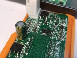 Zbliżenie na płytę PCB ze stacji lutowniczej T12OAS, widoczne są układy scalone, kondensator i oznaczenia elementów.