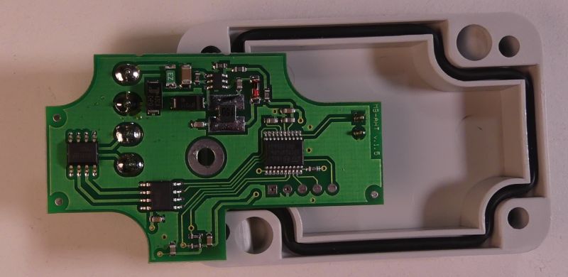Płytka drukowana z elementami elektronicznymi w otwartej plastikowej obudowie.