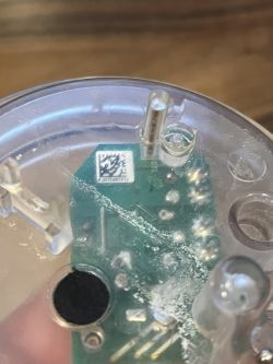 Zbliżenie na obwód drukowany, widoczne elementy elektroniczne i miedziany drucik oznaczony jako DT1.