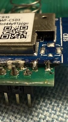 Small IC with pins soldered under a microscope, connected to a CB3S module.