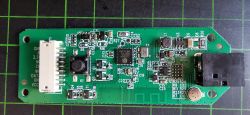 Electronic circuit board with various components on a green grid background.