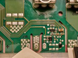 Uszkodzony fragment płyty PCB z zaznaczonymi elementami elektronicznymi