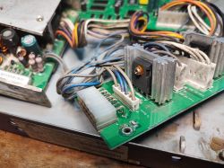 Zbliżenie na wnętrze starego switcha sieciowego, widoczne zabrudzone przewody, płytka PCB i aluminiowe radiatory.