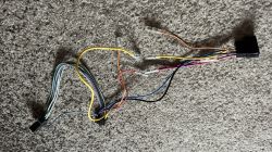 Trzy przewody od radia leżące na dywanie: żółty, czerwony i pomarańczowy, każdy z niepodłączoną końcówką.