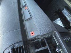 Zdemontowana deska rozdzielcza BMW X5 z widocznymi czerwonymi mocowaniami i wnęką po radiu