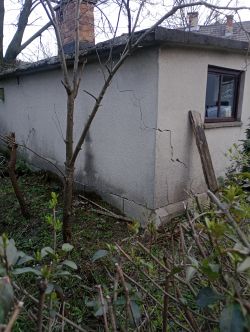 Zniszczona ściana garażu z pęknięciami i osiadaniem.