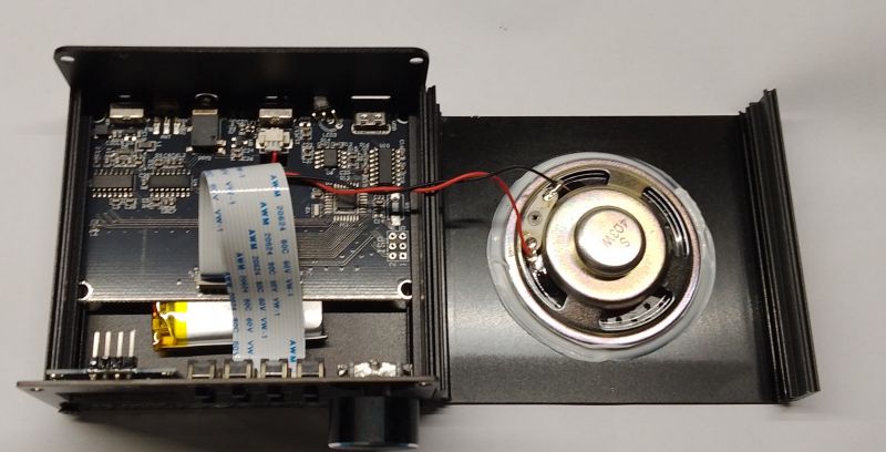 Wnętrze elektronicznego urządzenia z płytką drukowaną i głośnikiem.