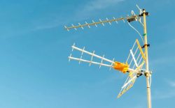 Kierunkowa antena telewizyjna zamontowana na maszcie, skierowana na niebieskie niebo