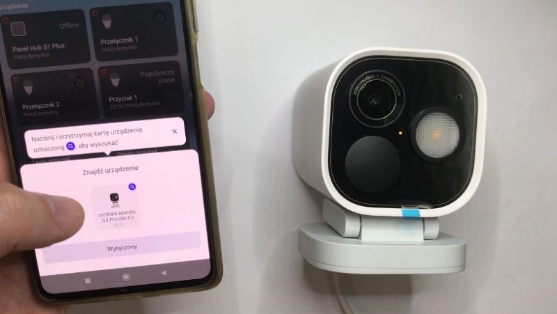 Smartfon z aplikacją do zarządzania urządzeniami obok kamery monitoringu