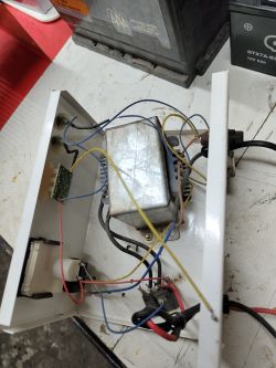 Wnętrze prostownika z odlutowanymi żółtymi przewodami zaznaczonymi do naprawy.