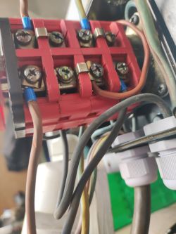 Zbliżenie na czerwony wyłącznik silnika z podłączonymi przewodami elektrycznymi.