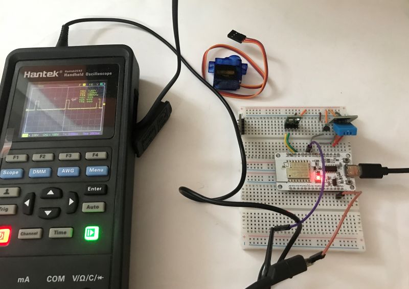 Handheld oscilloscope with signal graph and breadboard with electronic components.