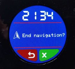 Okrągły ekran urządzenia pokazuje godzinę 21:34 i komunikat „End navigation?” z przyciskami.