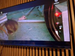 Telewizor TCL z poziomym ciemnym paskiem u dołu ekranu podczas odtwarzania filmu.
