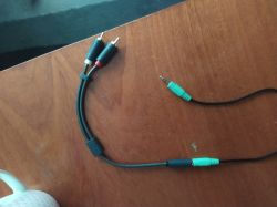 Kabel z wtykami chinch i aux na drewnianym stole.