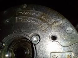 Zbliżenie metalowej obudowy urządzenia z widocznymi napisami w językach francuskim i niemieckim.