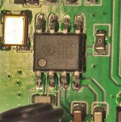 Close-up of an integrated circuit and surrounding components on a green printed circuit board.