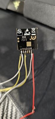 Chip labeled XHX 2023 with connected wires, one of which is red.