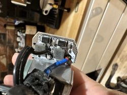 Zbliżenie na elementy elektroniki lampki rowerowej z odsłoniętą płytką drukowaną i widocznymi kablami.