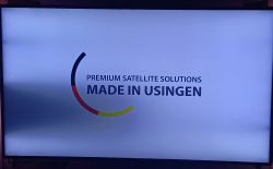Telewizor z logo i hasłem Premium Satellite Solutions Made in Usingen oraz zacienieniem po lewej stronie ekranu.
