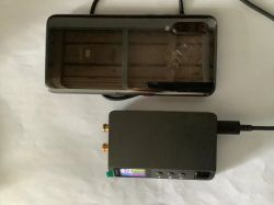 DP100 power supply next to Xiaomi smartphone on white background