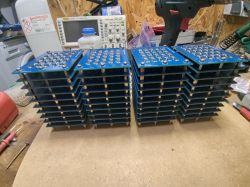 Stacks of blue electronic boards arranged on a workshop table.