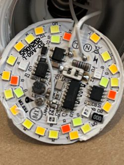 Close-up of the PCB of an LED bulb with multicolored diodes and visible damage.
