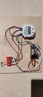 Hand-assembled electrical circuit on a wooden board with a digital timer.