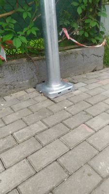 Podstawa metalowego słupa przymocowana do betonowego chodnika.