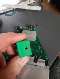 Spalony kondensator 0.27µF trzymany w ręku przed płytką obwodu.