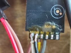 Close-up of an electronic module with visible pin labels: 3V3, GND, RX, TX, A1, A0.