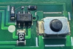 Zbliżenie na elementy elektroniczne na płytce PCB pilota FAAC XT4, w tym przycisk, rezystor SMD oznaczony „473” oraz układ scalony SOT-23-6 z napisem „BF II”.
