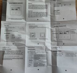 Unfolded English “WT200 Thermostat User Guide” photographed from above on a wooden surface