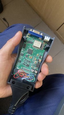 Osoba trzyma w ręku otwarte urządzenie elektroniczne z widoczną płytką PCB i układem WiFi.