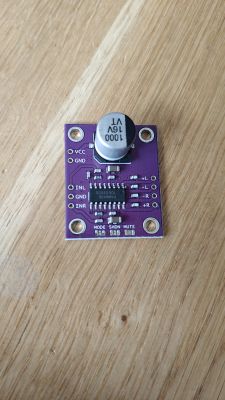 Purple PAM8406 amplifier module with large capacitor on a wooden surface