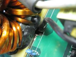 Zbliżenie na element elektroniczny z miedzianymi przewodami i płytką PCB z widoczną szczeliną.