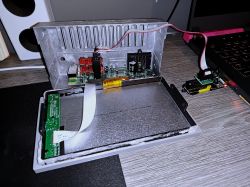 Open car radio case with display ribbon cable and wires connected to a memory programmer