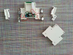 Photo of a disassembled white electronic device with visible interior and wires on a colorful background.
