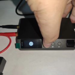 Close-up of powered-on DP100 power supply with visible buttons and connected cables
